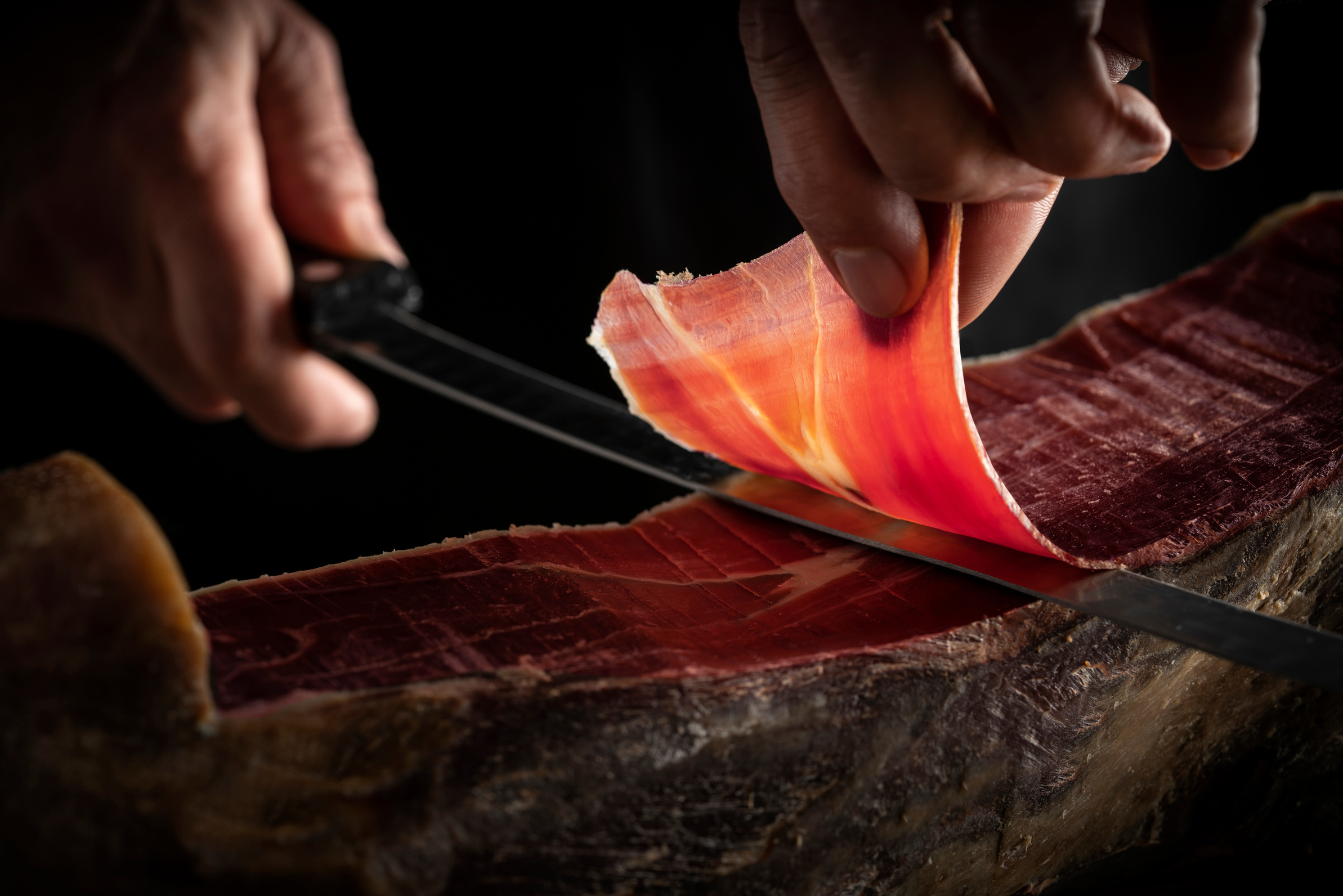 Iberian ham serrano ham slice cutting hands and knife